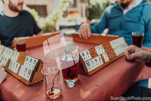 Image of A group of men drink traditional Turkish tea and play a Turkish game called Okey