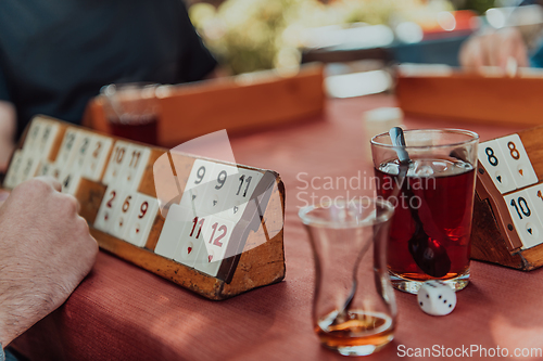 Image of A group of men drink traditional Turkish tea and play a Turkish game called Okey