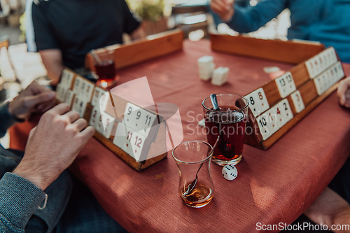 Image of A group of men drink traditional Turkish tea and play a Turkish game called Okey