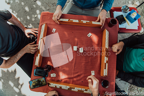 Image of A group of men drink traditional Turkish tea and play a Turkish game called Okey