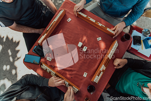 Image of A group of men drink traditional Turkish tea and play a Turkish game called Okey