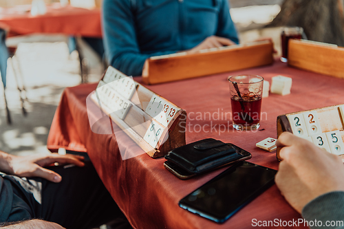 Image of A group of men drink traditional Turkish tea and play a Turkish game called Okey