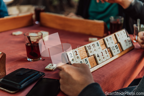 Image of A group of men drink traditional Turkish tea and play a Turkish game called Okey