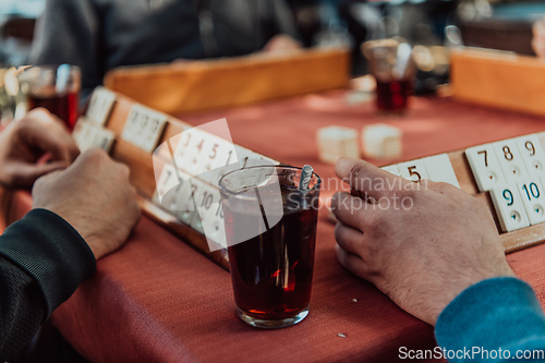 Image of A group of men drink traditional Turkish tea and play a Turkish game called Okey