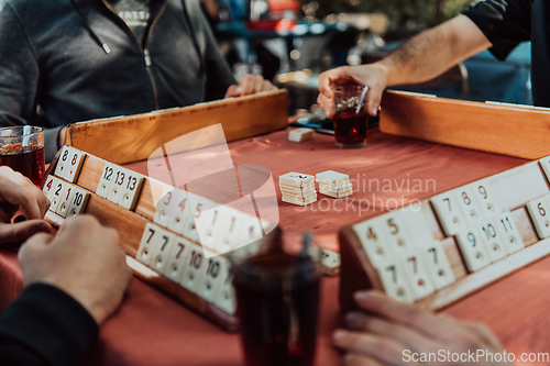 Image of A group of men drink traditional Turkish tea and play a Turkish game called Okey
