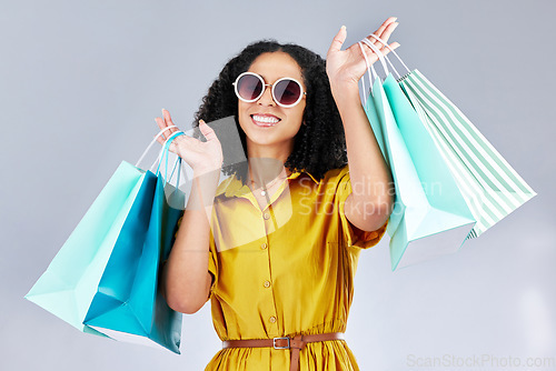 Image of Sunglasses, portrait and woman with shopping bag for fashion in studio isolated on a white background. Face smile, sales and African customer with gift, discount deal and clothes from retail store