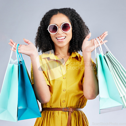 Image of Portrait, sunglasses and woman with shopping bags for fashion in studio isolated on a white background. Face smile, sales and African customer with gift, discount deal and stylish clothes from store