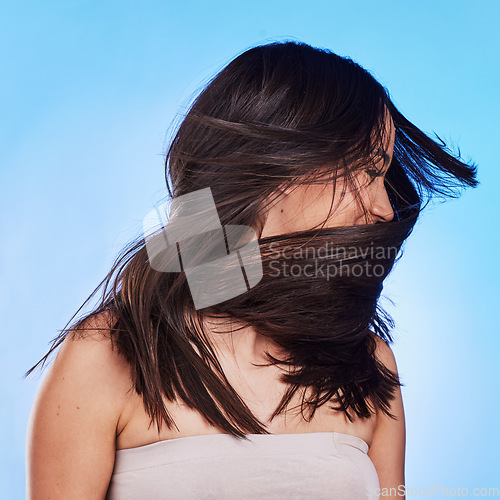 Image of Woman, shake hair and beauty with growth, shine and self care against a blue studio background. Natural cosmetics, female person or model satisfied with salon treatment, glow and health with wellness