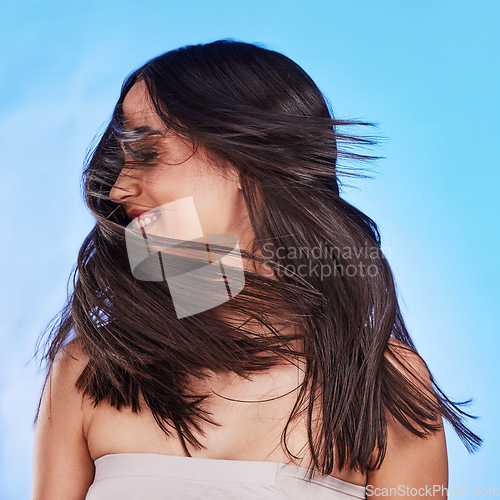 Image of Woman, shake hair and beauty with shine, volume and texture against a blue studio background. Growth, person and model satisfied with salon treatment, glow and change with self care, playful and fun