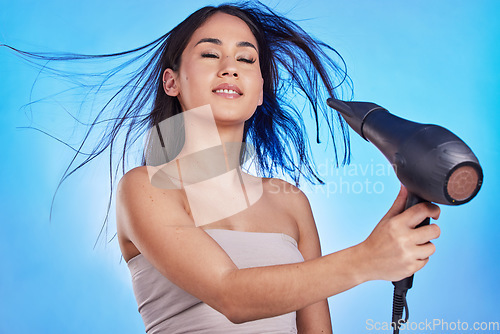 Image of Hair care, hairdryer and beauty of a woman in studio for cosmetics, self care and heat tools. Salon, hairdresser and a female model person with a dryer for shampoo results on a blue background