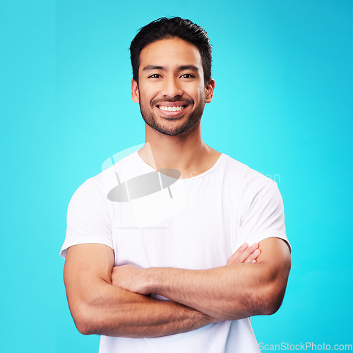 Image of Smile, confident and portrait of Asian man arms crossed with casual fashion isolated in a studio blue background. Relax, calm and young male person with cheerful or happy mindset and happiness