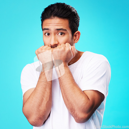 Image of Fear, scared and portrait of man nervous, anxiety or anxious due to crisis or stress isolated in a studio blue background. Worry, suspense and young male person hands in face for mistake reaction