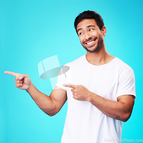 Image of Mockup, pointing and man with a smile, thinking and choice against a blue studio background. Male person, decision or model with product placement, hand gesture and presentation with sign and showing