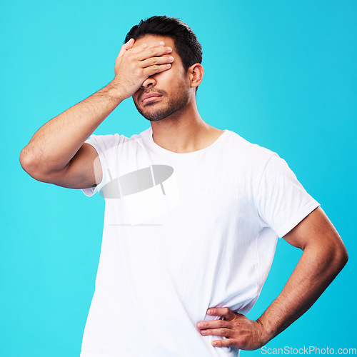 Image of Man, face palm and mistake in studio with thinking, regret and anxiety for fail by blue background. Young guy, student and cover eyes with stress, memory and shame for bad decision with depression