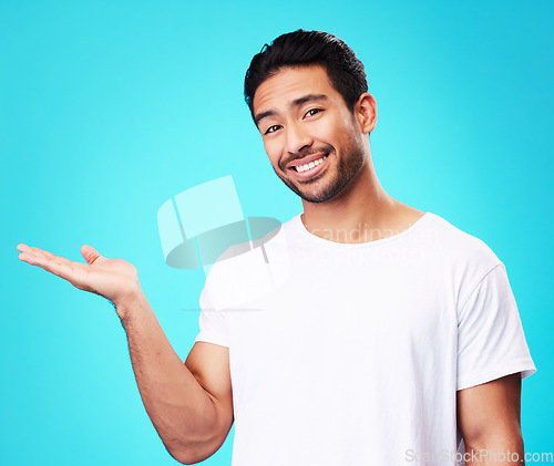 Image of Gesture, hand and portrait of a man on a blue background for marketing, advertising or a logo. Smile, promo and an Asian person showing mockup space for presentation isolated on a studio backdrop