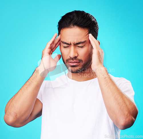 Image of Stress, pain and man with a headache, burnout and health problem on a blue studio background. Male person, anxiety and model with a migraine, frustrated and tension with strain, fatigue and pressure