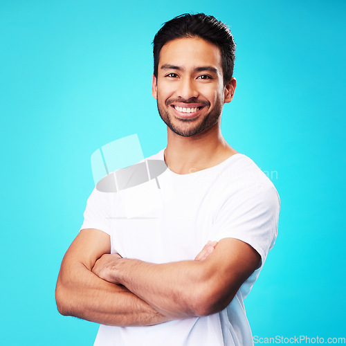 Image of Smile, happy and portrait of Asian man arms crossed with casual fashion isolated in a studio blue background. Relax, calm and young male person proud or confident mindset, natural and happiness
