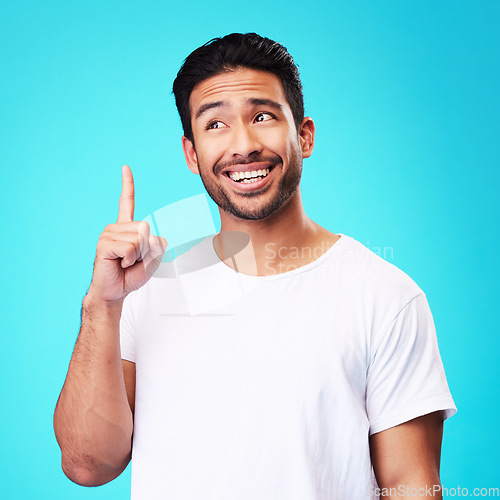 Image of Mockup, pointing up and man with a smile, thinking and solution against a blue studio background. Male person, decision and model with hand gesture, opportunity or option with sign, choice or showing