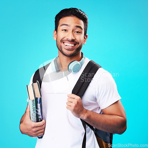 Image of Indian, college student and portrait in studio with backpack for university, education and studying with books on blue background. Happy, man and person excited to study and learn for future goals