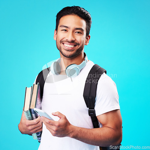 Image of Indian, college student and portrait with phone in studio and backpack for university, education and connection on blue background. Happy, man and person excited to study and learn for future goals