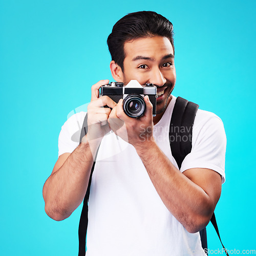 Image of Portrait, creativity and man with a camera, photography and artist against a blue studio background. Face, male person and model with vintage technology, journalist and photographer with inspiration