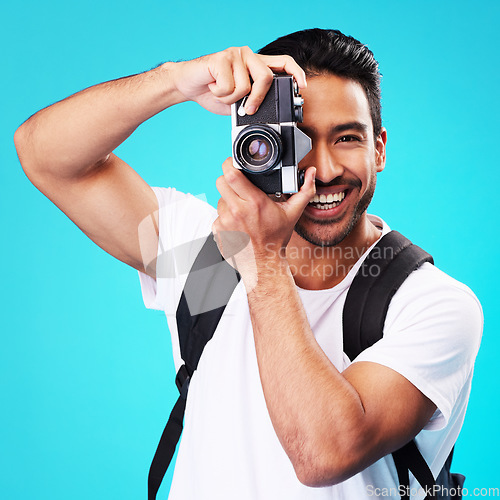 Image of Portrait, smile and man with a camera, photography and taking picture against a blue studio background. Face, male person or model with creativity, vintage technology or photographer with inspiration