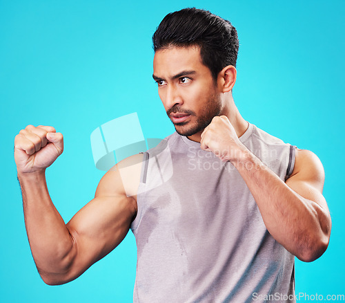 Image of Fitness, man and fighter training, sports and exercise against a blue studio background. Male person, sweating or serious athlete with power, strong or energy with workout goals, fight or competition