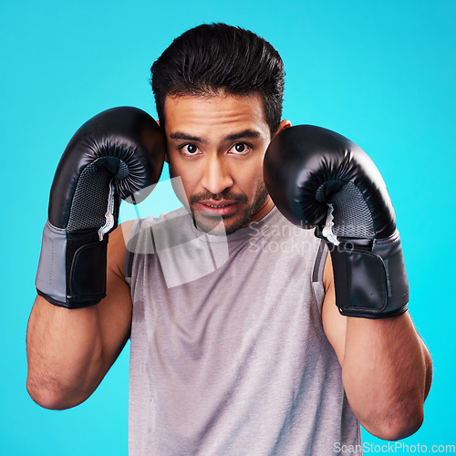 Image of Boxing, man and fighter training, portrait or challenge against a blue studio background. Male person, boxer or serious athlete with power, face or energy with workout goals, fight or strong champion