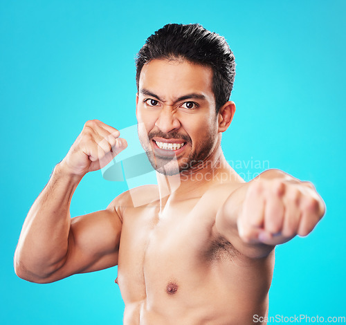 Image of Man, shirtless and martial arts in studio portrait with power, punch and anger by blue background. Guy, mma and muscle for fight, contest or sport with exercise, training and workout for competition