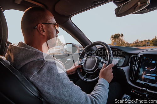 Image of A man with a sunglasses driving a car at sunset. The concept of car travel