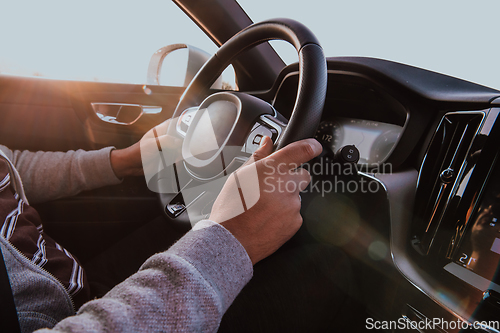 Image of Close up man hand driving a car at sunset. The concept of car travel