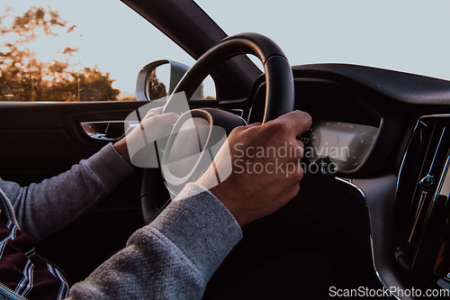 Image of Close up man hand driving a car at sunset. The concept of car travel