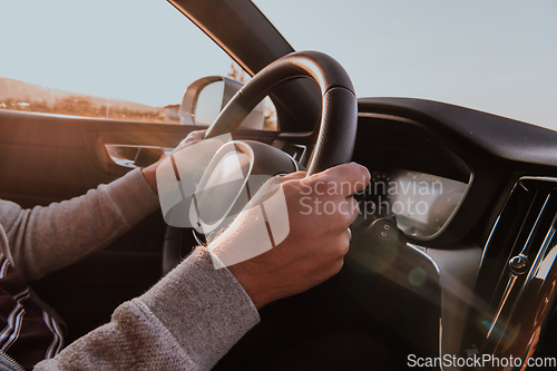 Image of Close up man hand driving a car at sunset. The concept of car travel