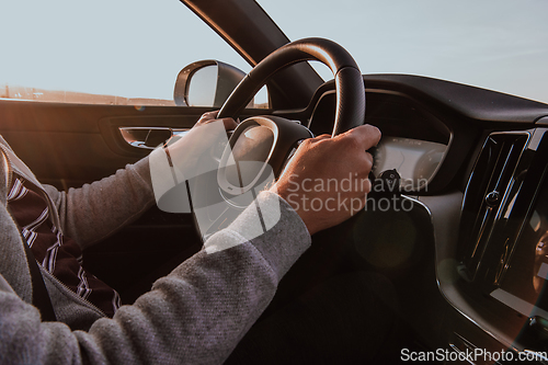 Image of Close up man hand driving a car at sunset. The concept of car travel