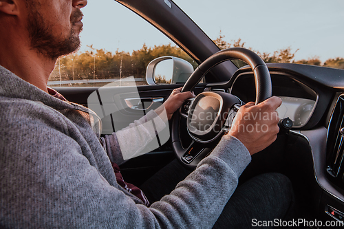 Image of Close up man hand driving a car at sunset. The concept of car travel