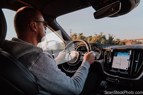 Image of A man with a sunglasses driving a car at sunset. The concept of car travel