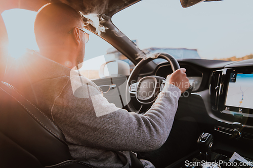 Image of A man with a sunglasses driving a car at sunset. The concept of car travel