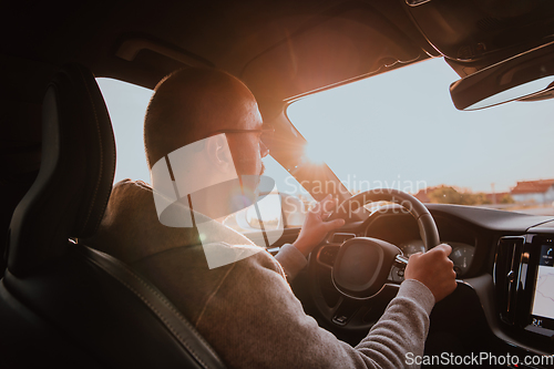 Image of A man with a sunglasses driving a car at sunset. The concept of car travel