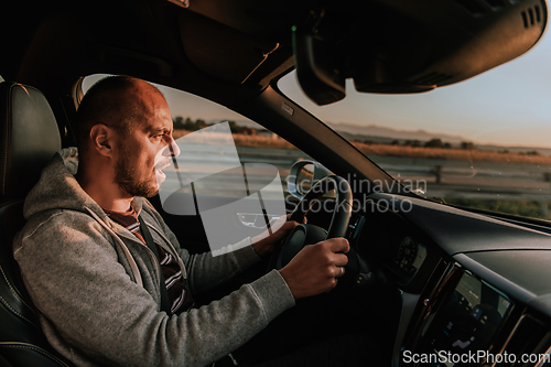 Image of A man with a sunglasses driving a car at sunset. The concept of car travel