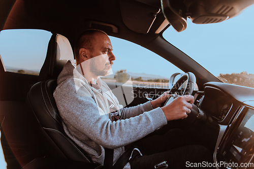 Image of A man with a sunglasses driving a car at sunset. The concept of car travel