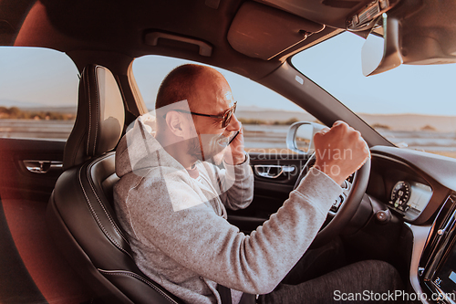 Image of The driver receives happy information while talking on the smartphone while driving the car