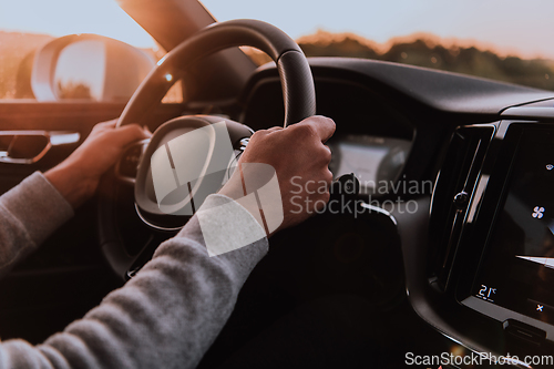 Image of Close up man hand driving a car at sunset. The concept of car travel