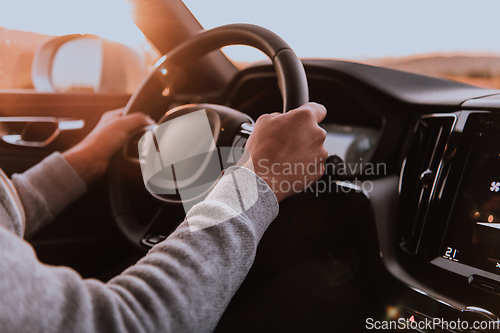 Image of Close up man hand driving a car at sunset. The concept of car travel