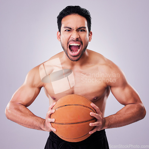 Image of Portrait, basketball and a sports man shouting in studio on a gray background for training or a game. Fitness, body and aggression with a young male athlete holding a ball while screaming in anger