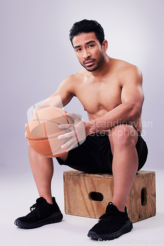 Image of Portrait, fitness and basketball with a man on a box in studio on a gray background for training or a game. Exercise, workout or mindset and a young male sports athlete holding a ball with focus