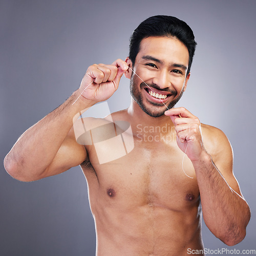 Image of Flossing teeth, studio portrait or happy man with oral health hygiene, wellness grooming or tooth treatment string. Morning bathroom routine, aesthetic smile or dental care person on gray background