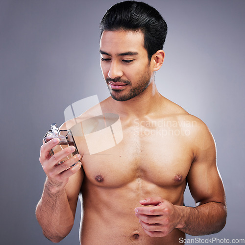 Image of Topless, cosmetics or man with cologne for beauty or self care isolated on studio background. Wellness, male person or Asian model with luxury body perfume spray with fragrance bottle or grooming