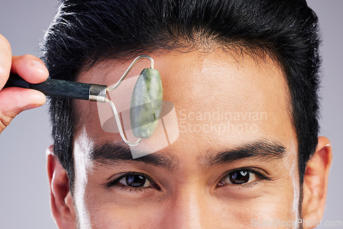 Image of Man, portrait or face massage with roller or quartz product for healthy skincare on studio background. Forehead, crystal stone treatment or male model with facial dermatology cosmetic for beauty glow