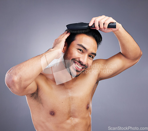 Image of Portrait, beauty or happy man brushing hair in grooming with salon haircare product on studio background. Smile, brush or confident healthy Asian male model with cool hairstyle in morning routine