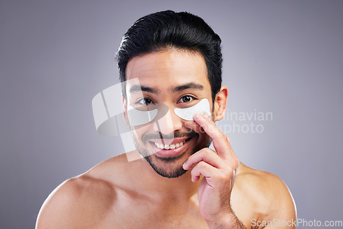 Image of Portrait, skincare or happy man with eye patch for beauty or wellness isolated on studio background. Cosmetics, smile or model with facial collagen pads or dermatology product for anti aging or glow